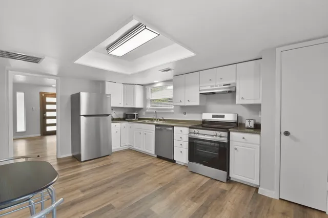 a kitchen with granite countertop a refrigerator stove top oven and sink