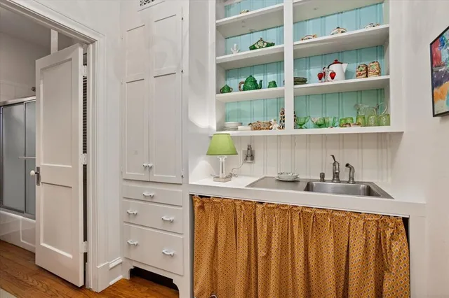 a kitchen with white cabinets and wooden floor