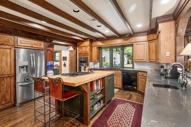 a kitchen with stainless steel appliances granite countertop a sink and wooden cabinets