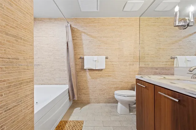 a bathroom with a granite countertop sink a toilet and a mirror