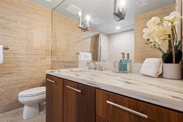 a bathroom with a sink a granite top and stainless steel appliances