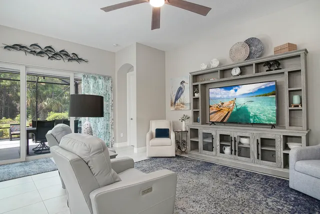 a living room with furniture a flat screen tv and a floor to ceiling window