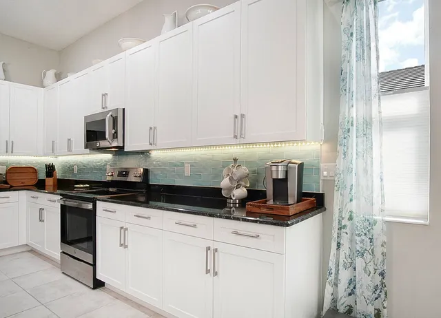 a kitchen with granite countertop white cabinets and stainless steel appliances