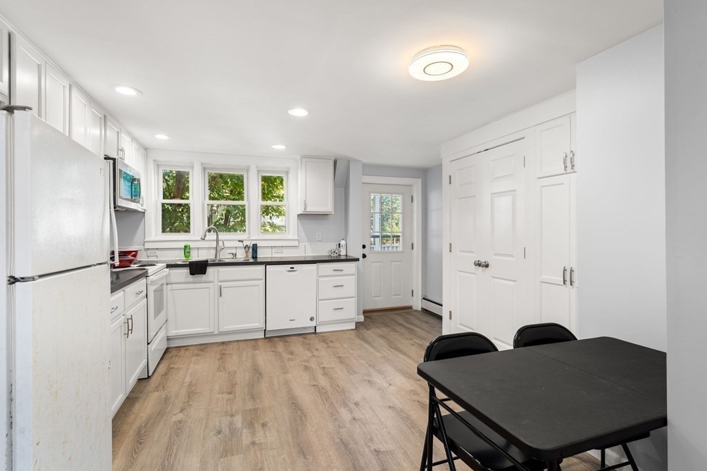 129 Friend Street Amesbury, MA 01913 - Photo 21 of 37 a kitchen with a refrigerator a sink dishwasher with a dining table and chairs