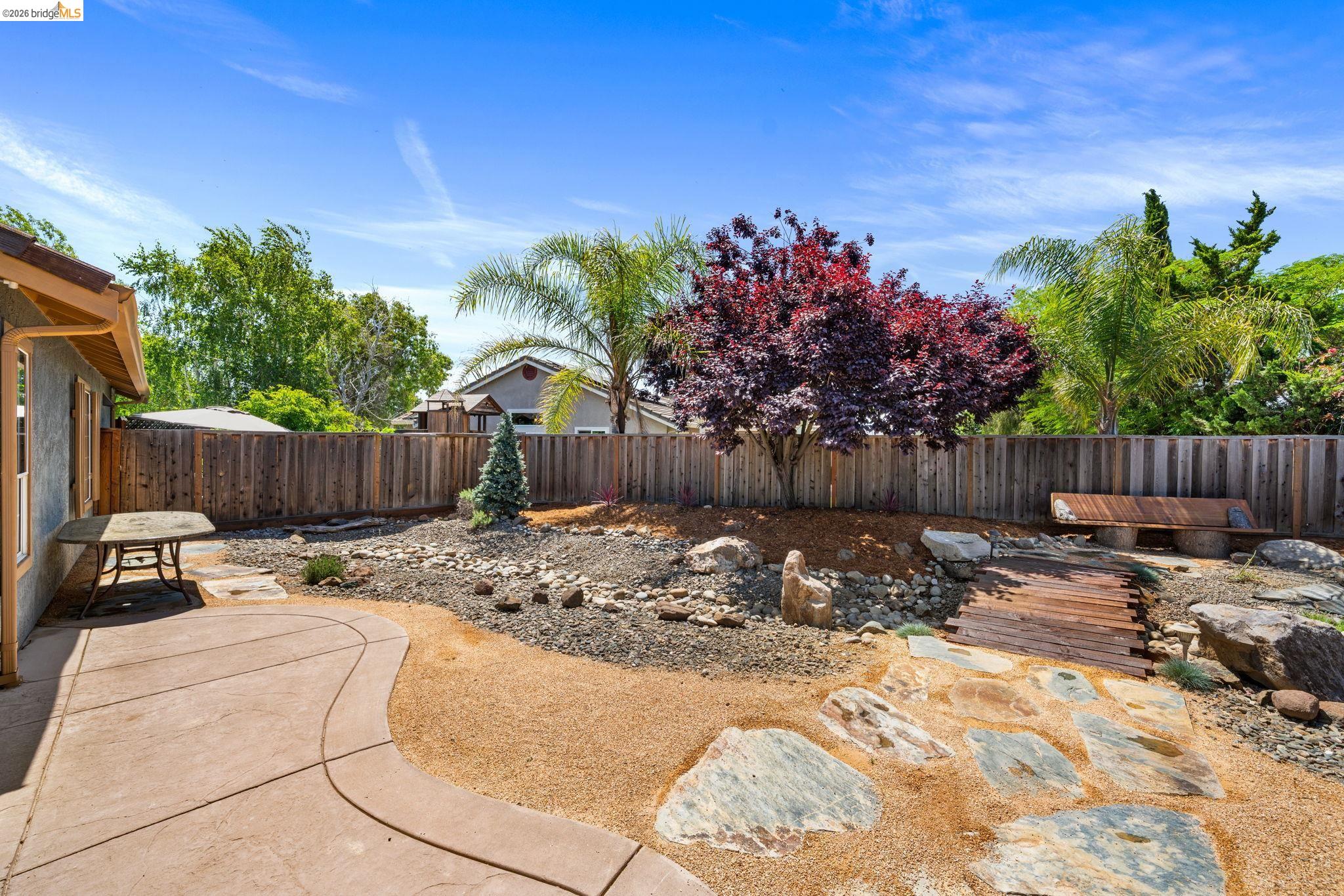 1186 El Rio Court Livermore, CA 94551 - Photo 41 of 60 Expansive backyard featuring a concrete patio with curved edges, a decorative rock garden, and mature trees