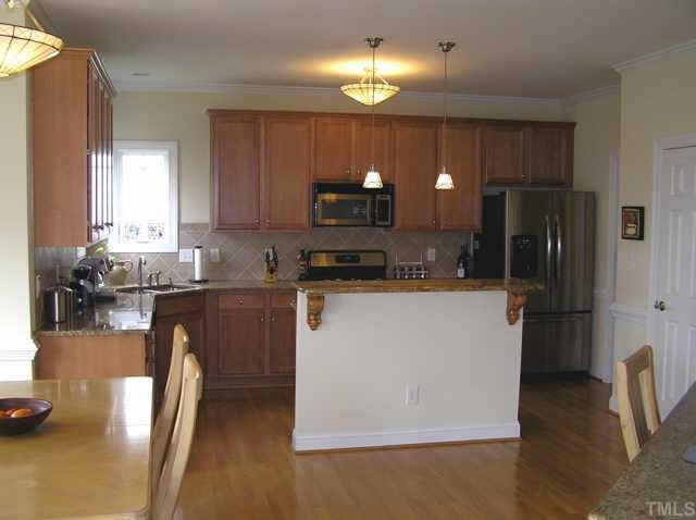 310 Challenge Raleigh, NC 27603 - Photo 6 of 10 Large kitchen with views of golf course from large corner stainless sink. Tons of maple cabinets, w/easy-glide drawers, granite countertops and tile backsplash. Large island with step-up bar. Stainless appliances, gas range and nice size pantry. Other