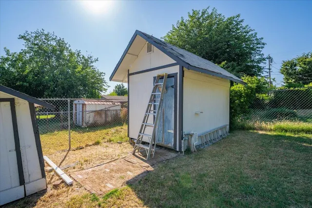 a view of backyard with small cabin and wooden fence