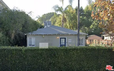 a front view of a house with a yard and trees