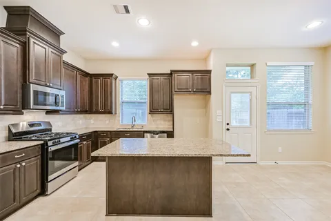 a kitchen with stainless steel appliances granite countertop a stove a sink and a microwave