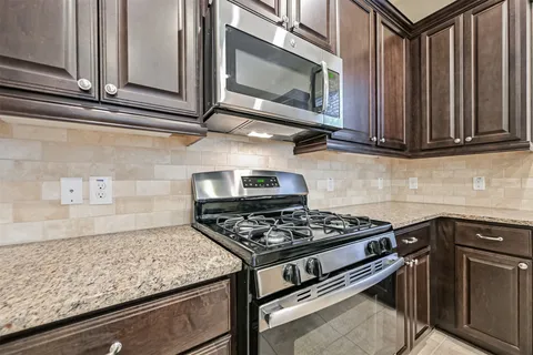 a kitchen with granite countertop cabinets and steel stove top oven