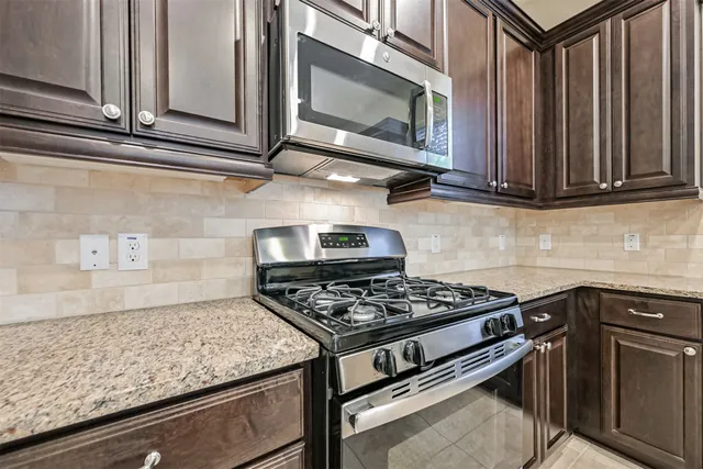 a kitchen with granite countertop cabinets and steel stove top oven