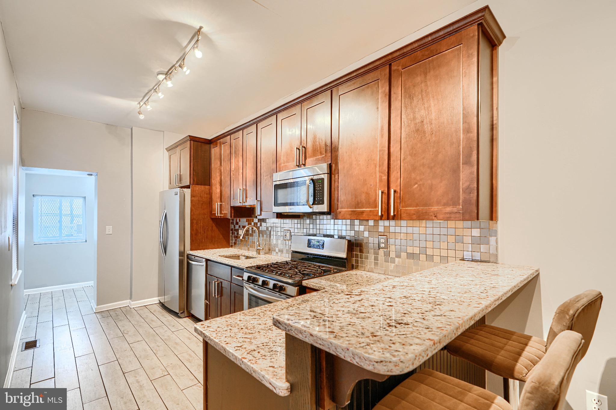 1410 East Oliver Street Baltimore, MD 21213 - Photo 13 of 40 a kitchen with stainless steel appliances granite countertop a stove refrigerator sink and cabinets