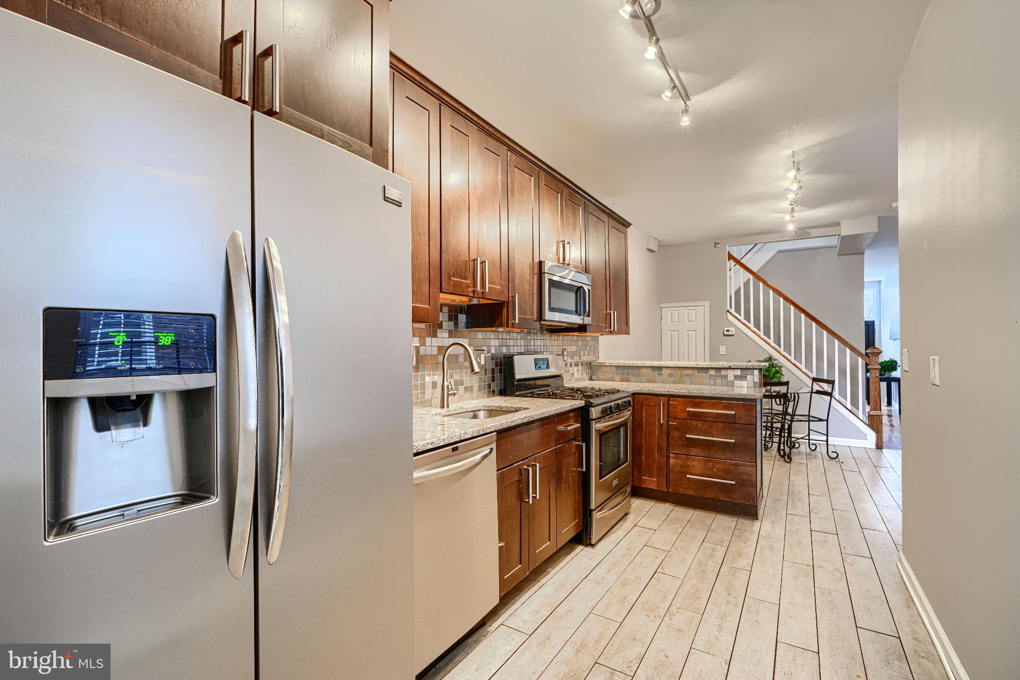 1410 East Oliver Street Baltimore, MD 21213 - Photo 16 of 40 a kitchen with stainless steel appliances granite countertop a refrigerator a stove and a wooden floors