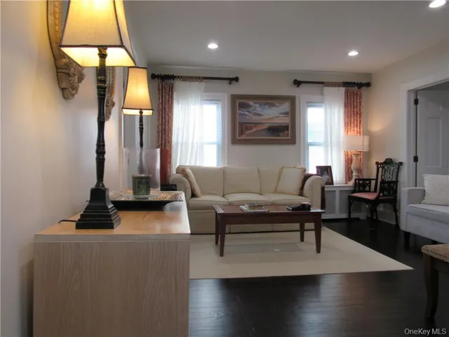 a living room with couches and a flat screen tv with kitchen view