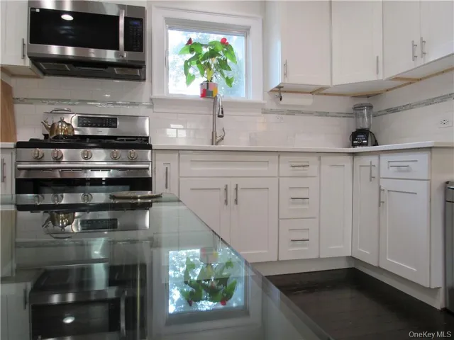 a kitchen with stainless steel appliances granite countertop a sink a stove and a microwave