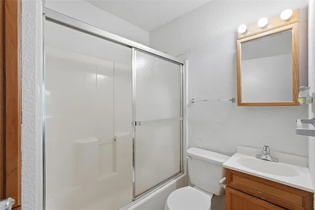 a bathroom with a toilet shower vanity and a sink