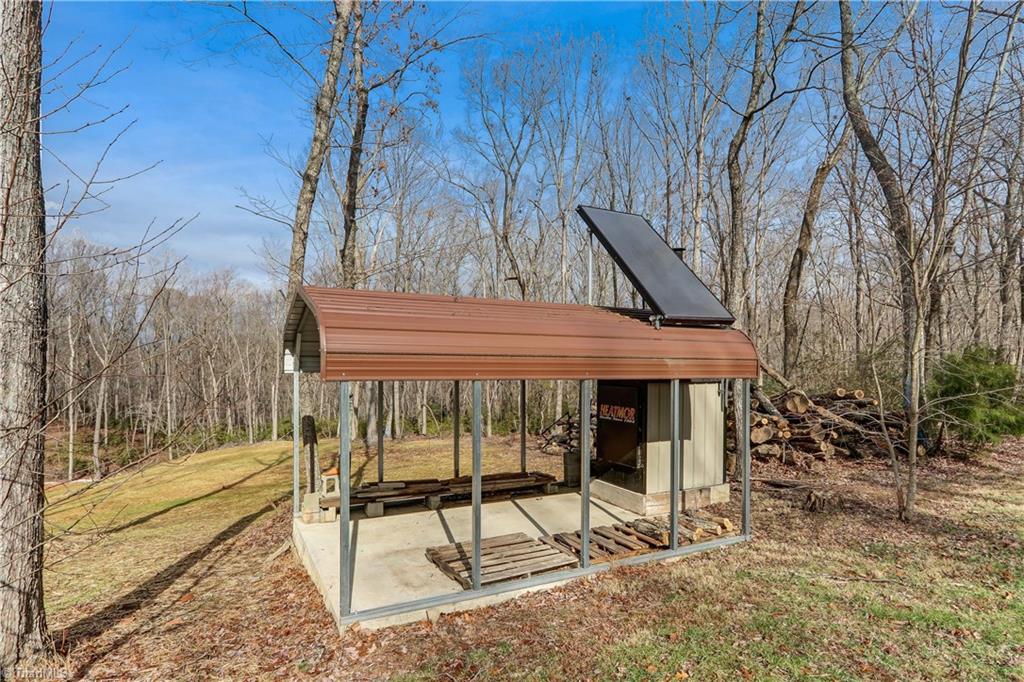 8605 Tuttle Ridge Road Germanton, NC 27019 - Photo 25 of 30 Covered storage for wood for the wood burning stove and the solar panel that is one of the sources of energy for the water heater.