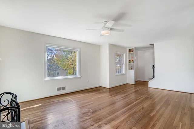an empty room with wooden floor chandelier and windows