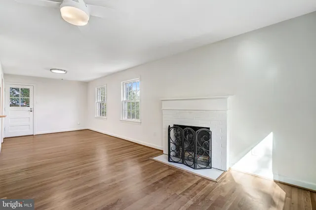 an empty room with wooden floor fireplace and windows