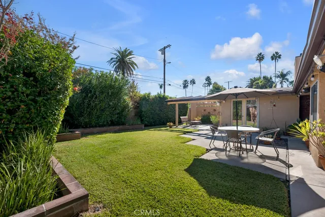 a view of a patio with table and chairs potted plants and large tree