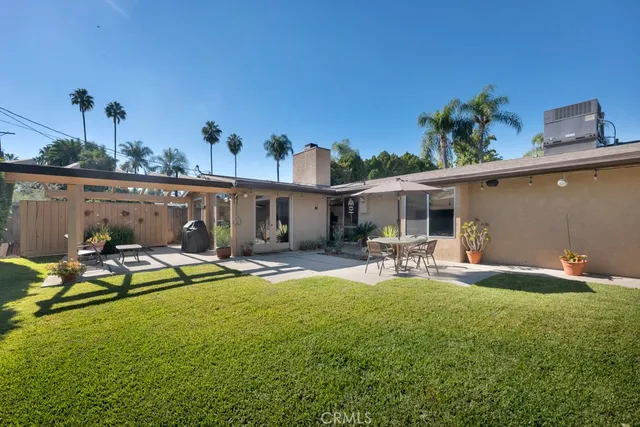 a view of a backyard with couches plants and large trees