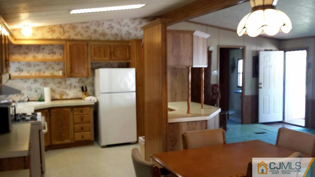15 Longfellow Road, Unit 15 North Brunswick, NJ 08902 - Photo 2 of 12 a kitchen with stainless steel appliances granite countertop a refrigerator a sink dishwasher a stove and a dining table with wooden floor