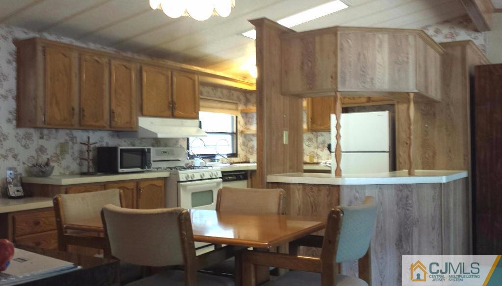 15 Longfellow Road, Unit 15 North Brunswick, NJ 08902 - Photo 6 of 12 a kitchen with a table chairs and microwave