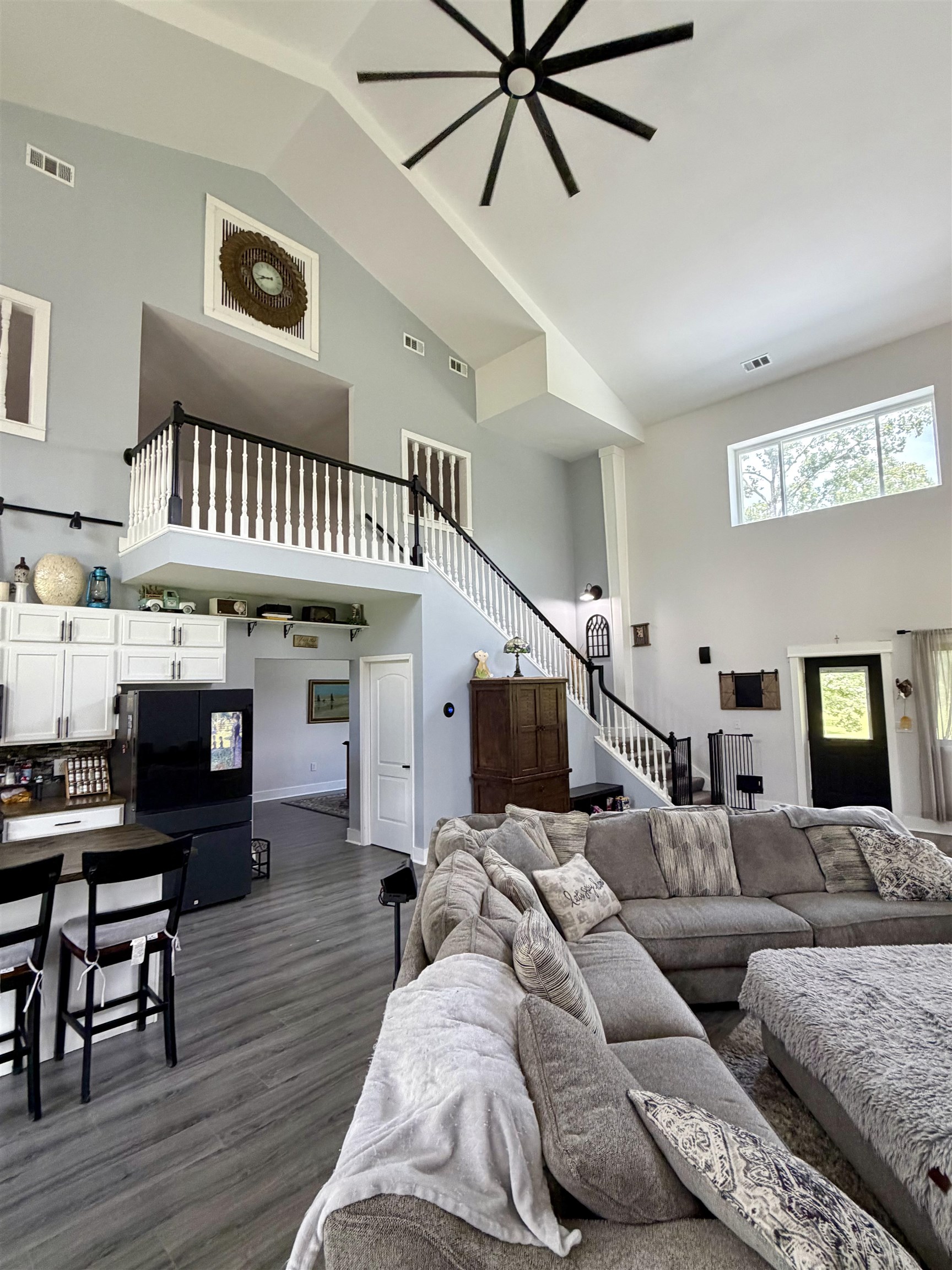 3670 Peavine Road Middleton, TN 38052 - Photo 5 of 36 Two-story great room featuring vaulted ceilings, a prominent ceiling fan, a second-story balcony with white balusters and black handrails, and wood-finish flooring