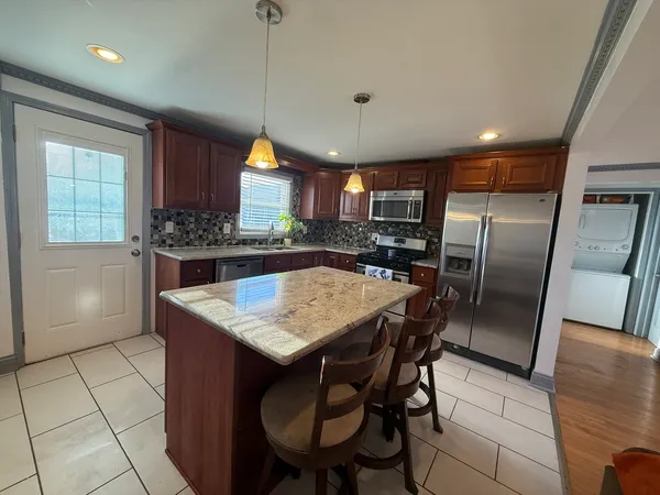 a kitchen with stainless steel appliances granite countertop a refrigerator a sink a stove and a refrigerator