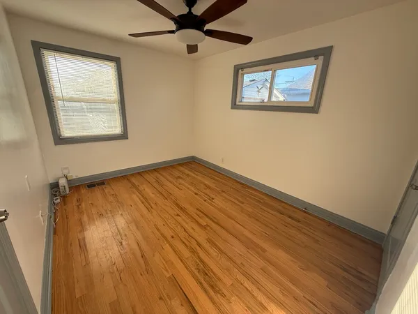 an empty room with wooden floor closet and windows