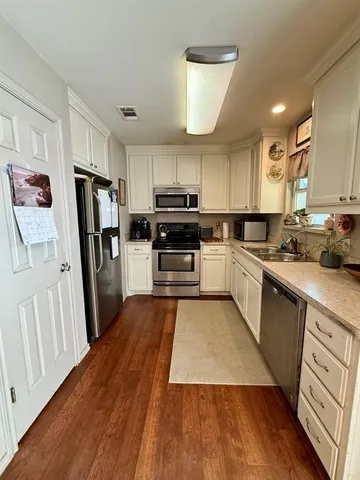 a kitchen with wooden floors appliances a sink and cabinets