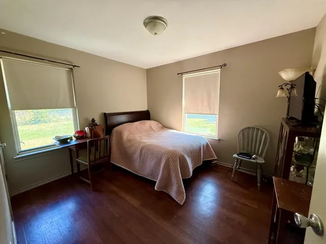 a bedroom with a bed a chair and a large window