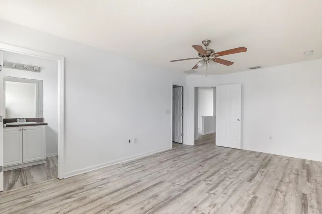 a view of a room with wooden floor and a ceiling fan