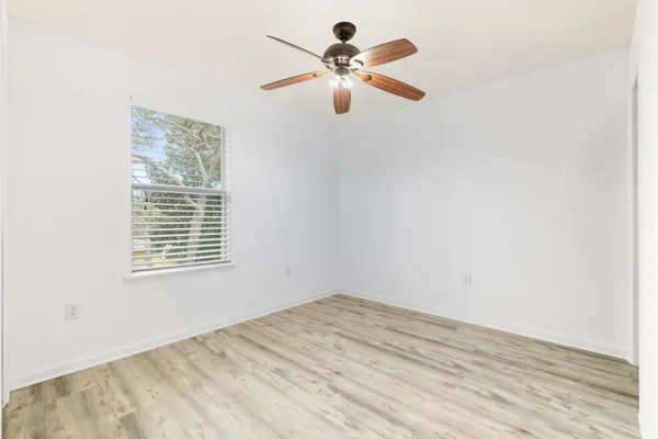 a view of a room with wooden floor and a ceiling fan