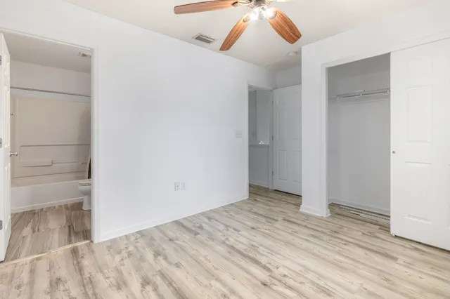 an empty room with wooden floor closet and chandelier fan