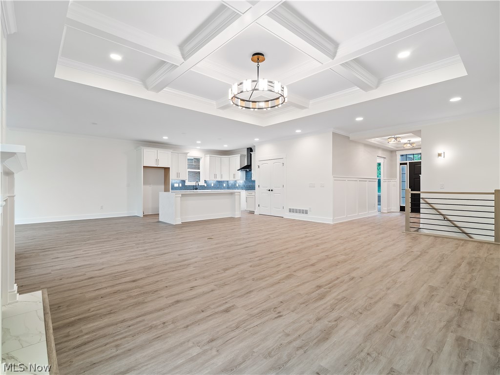 32 Brookside Lane North Ridgeville, OH 44039 - Photo 25 of 50 Unfurnished living room with recessed lighting, a chandelier, beamed ceiling, coffered ceiling, and light wood-style flooring