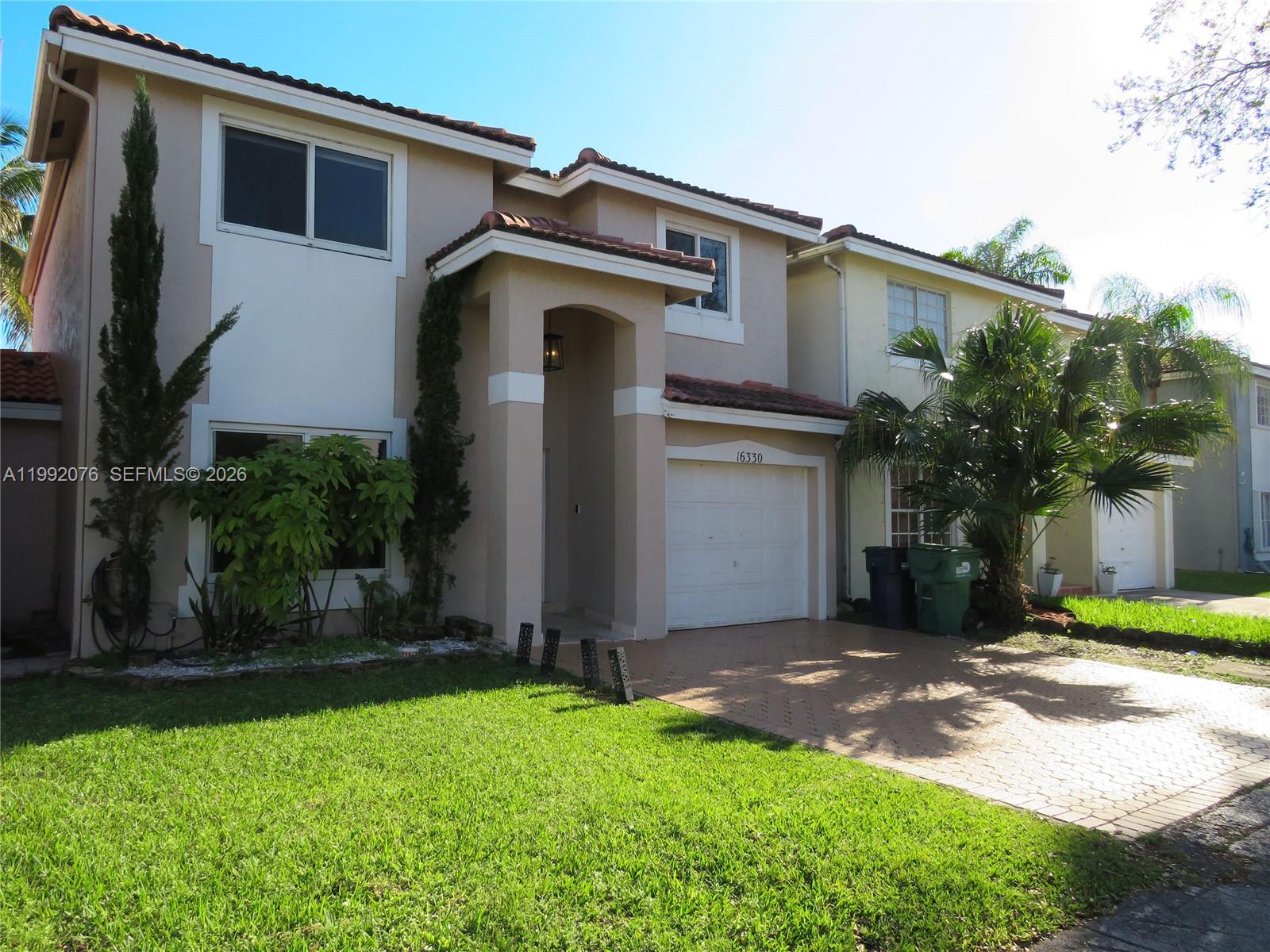 16330 Southwest 102nd Street Miami, FL 33196 - Photo 2 of 30 a front view of a house with a yard and garage