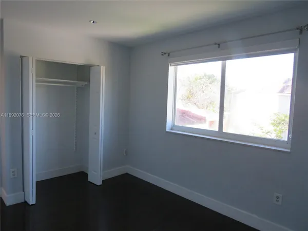 an empty room with wooden floor chandelier fan and windows