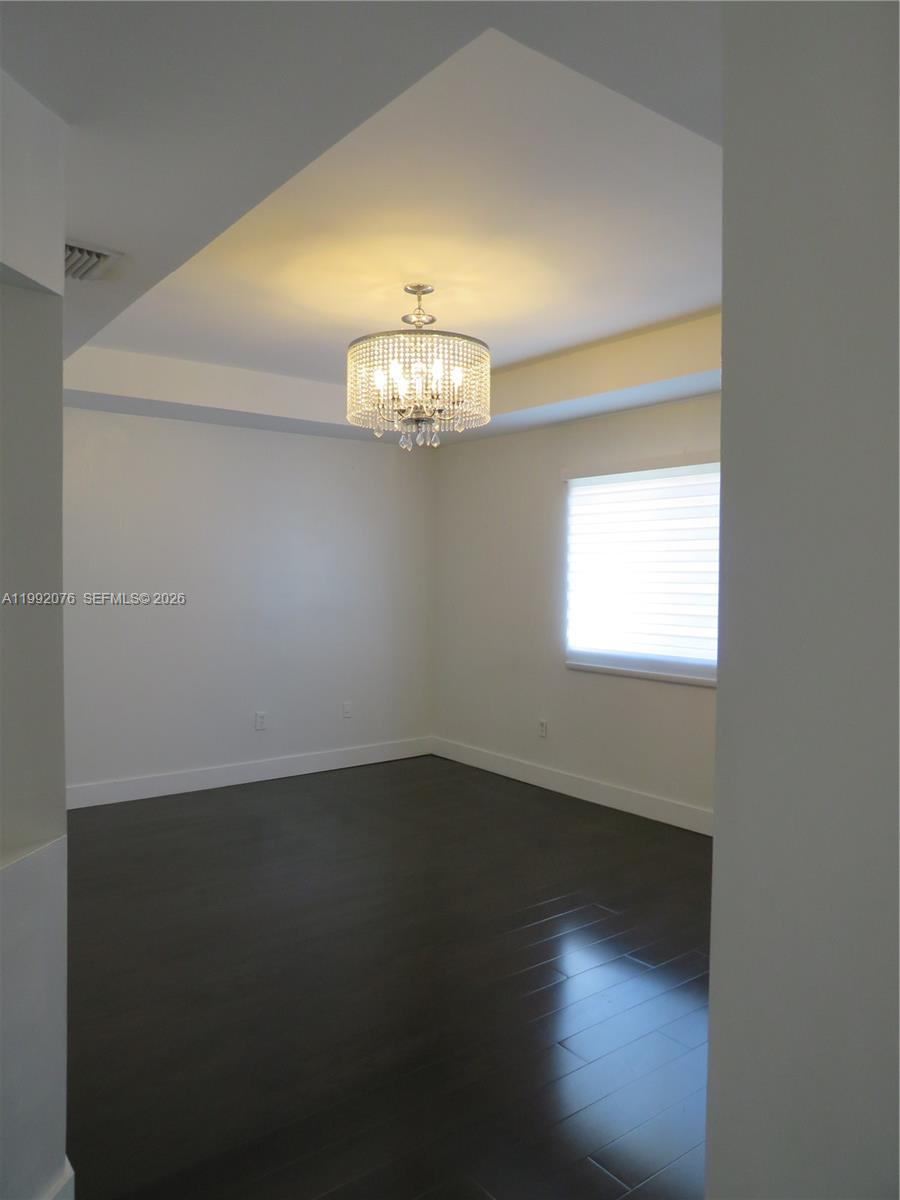 16330 Southwest 102nd Street Miami, FL 33196 - Photo 25 of 30 an empty room with wooden floor chandelier fan and windows