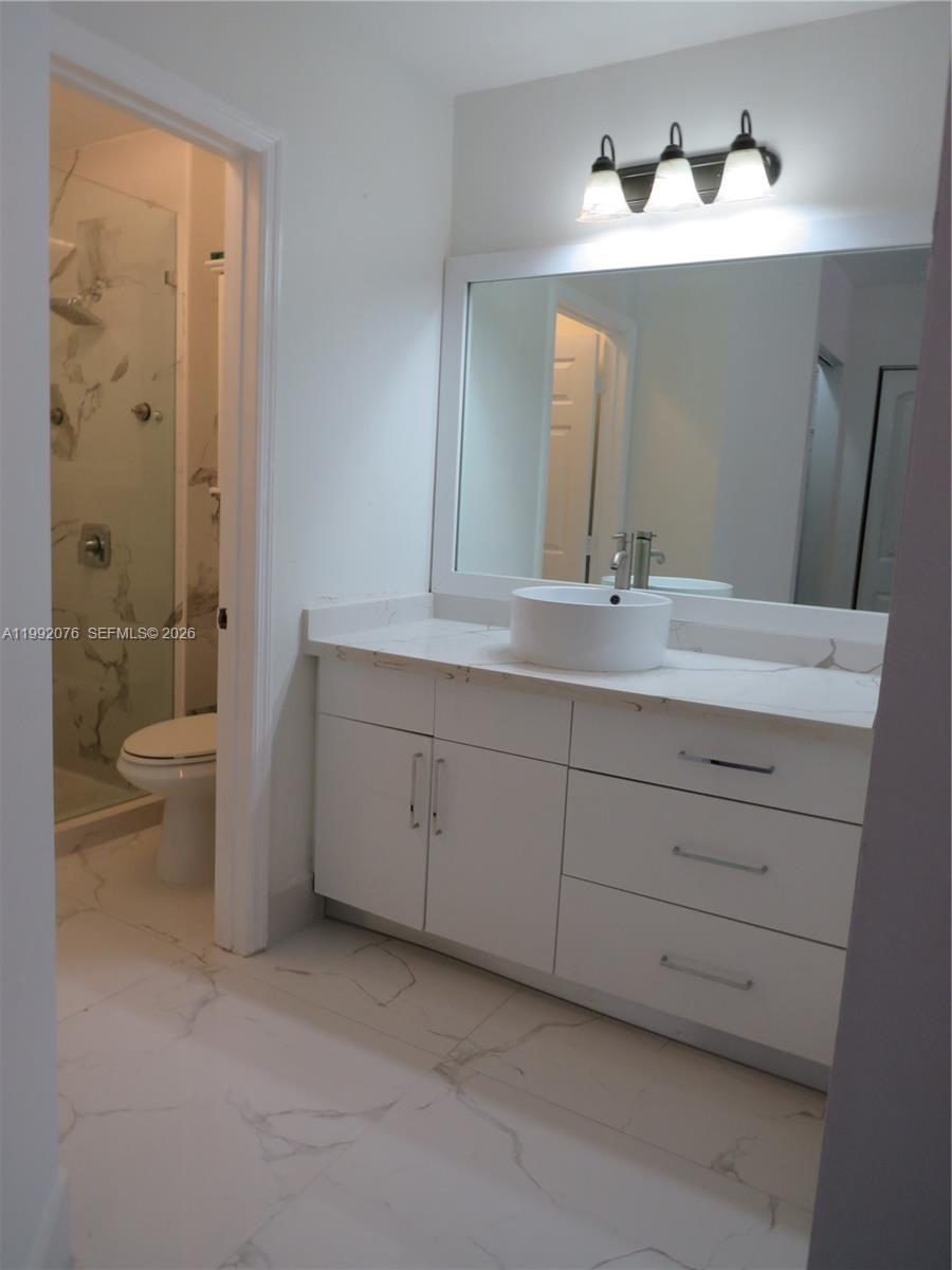 16330 Southwest 102nd Street Miami, FL 33196 - Photo 27 of 30 a bathroom with a double vanity sink a toilet and a shower