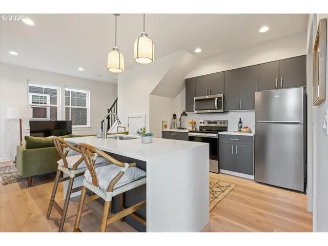 a kitchen with stainless steel appliances granite countertop a refrigerator a sink dishwasher a stove and a refrigerator with wooden floor