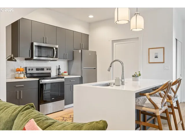 a kitchen with stainless steel appliances a stove a sink a microwave and a refrigerator