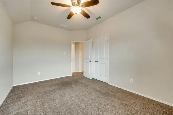 a view of an empty room and chandelier fan