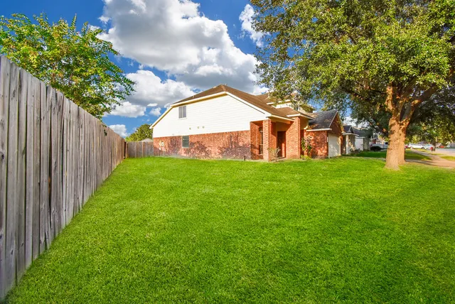 a view of a backyard with large trees and a barn in it