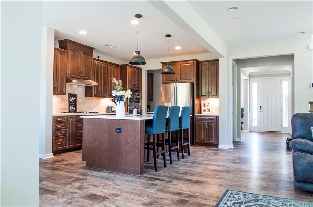 5554 Braddock Ml Way Lancaster, SC 29720 - Photo 7 of 33 a kitchen with stainless steel appliances granite countertop a refrigerator a sink dishwasher a dining table and chairs with wooden floor