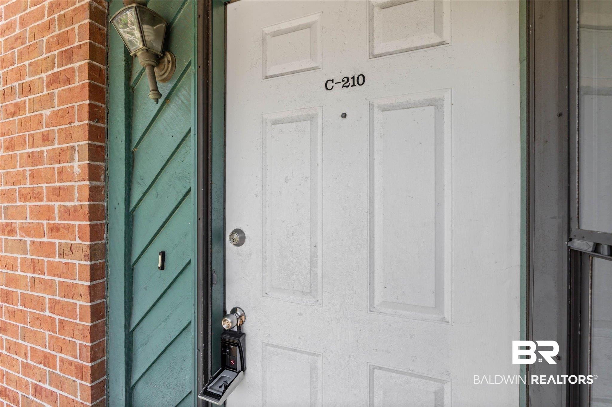 500 Grant Street, Unit C210 Daphne, AL 36526 - Photo 2 of 26 White paneled entry door with unit number C-210, complemented by a decorative wall-mounted lantern light fixture