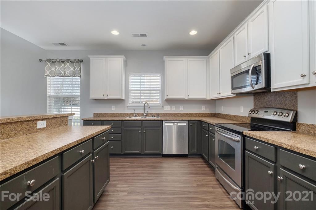 17107 Hampton Trace Road Huntersville, NC 28078 - Photo 2 of 18 a kitchen with stainless steel appliances granite countertop a sink dishwasher a stove top oven a refrigerator with white cabinets and wooden floor