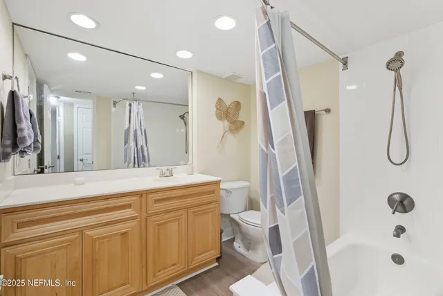 a bathroom with a double vanity sink a toilet a mirror and shower