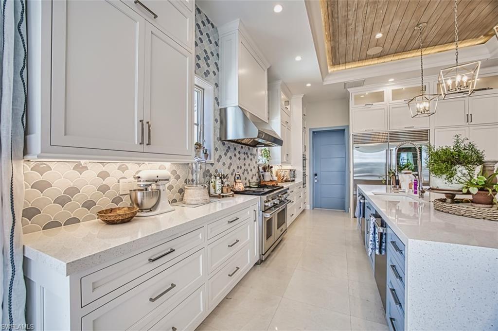 1340 Jewel Naples, FL 34102 - Photo 8 of 44 Kitchen featuring high quality appliances, a raised ceiling, wall chimney range hood, decorative backsplash, and white cabinets