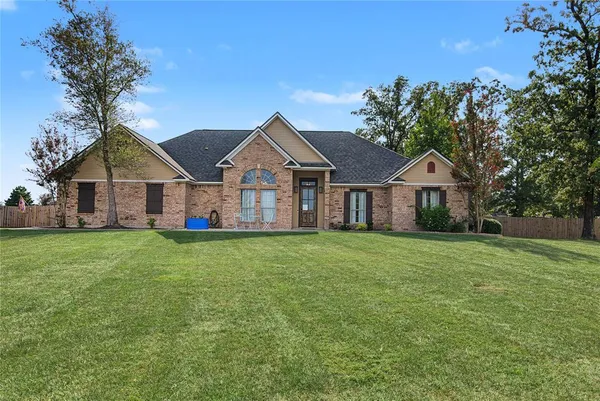 a view of a house with a big yard and large trees